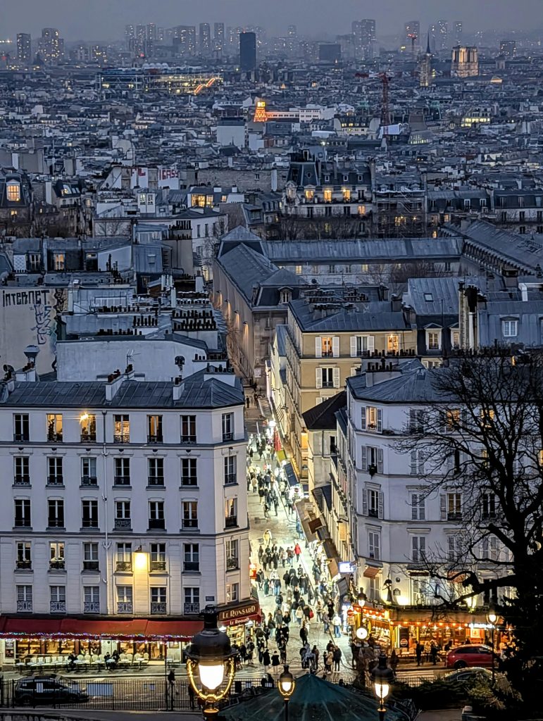 A bustling evening view of Montmartre's lively streets and iconic Parisian rooftops